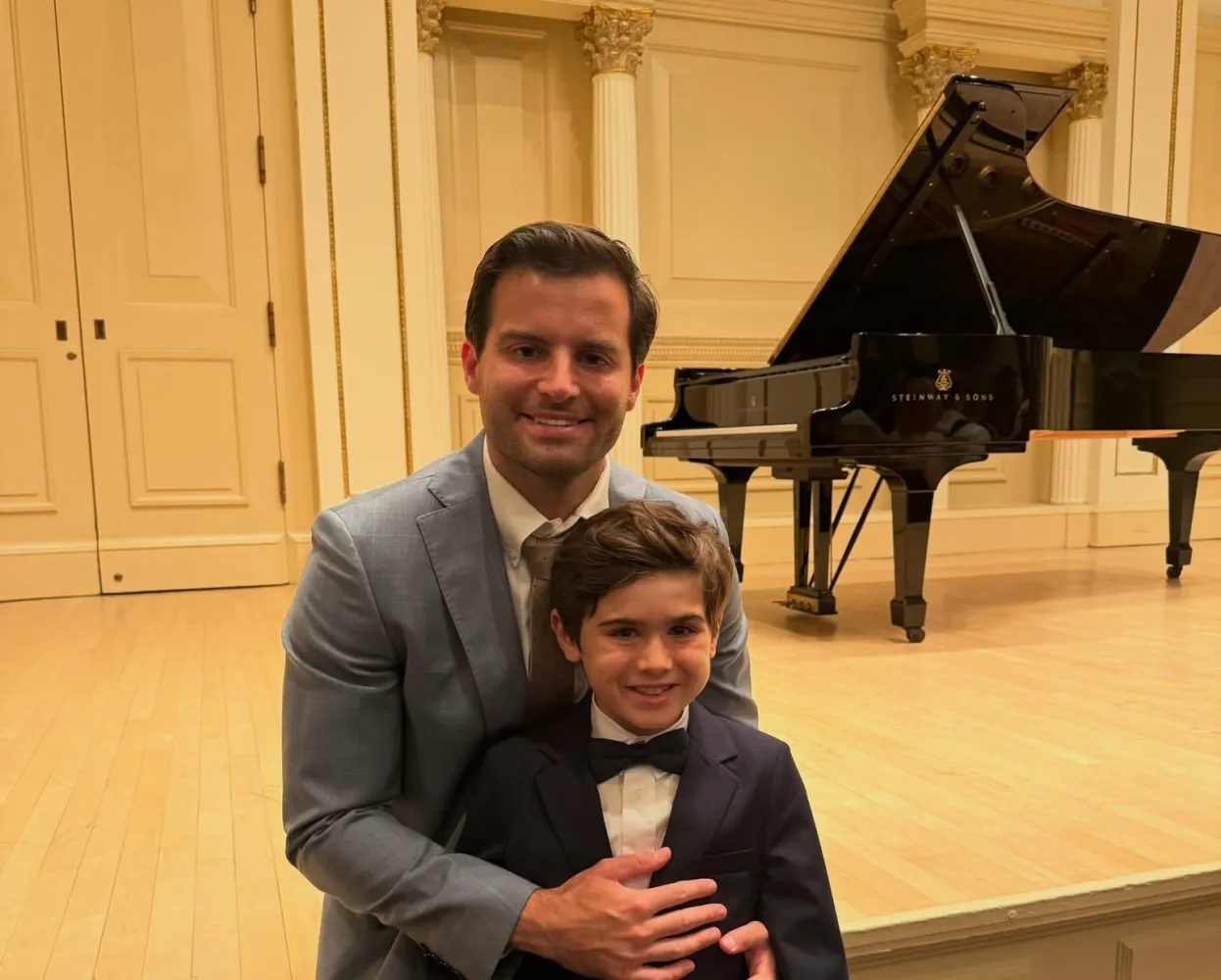 Dr. Jeffrey Tapley with his son on a recital stage in front of a grand piano